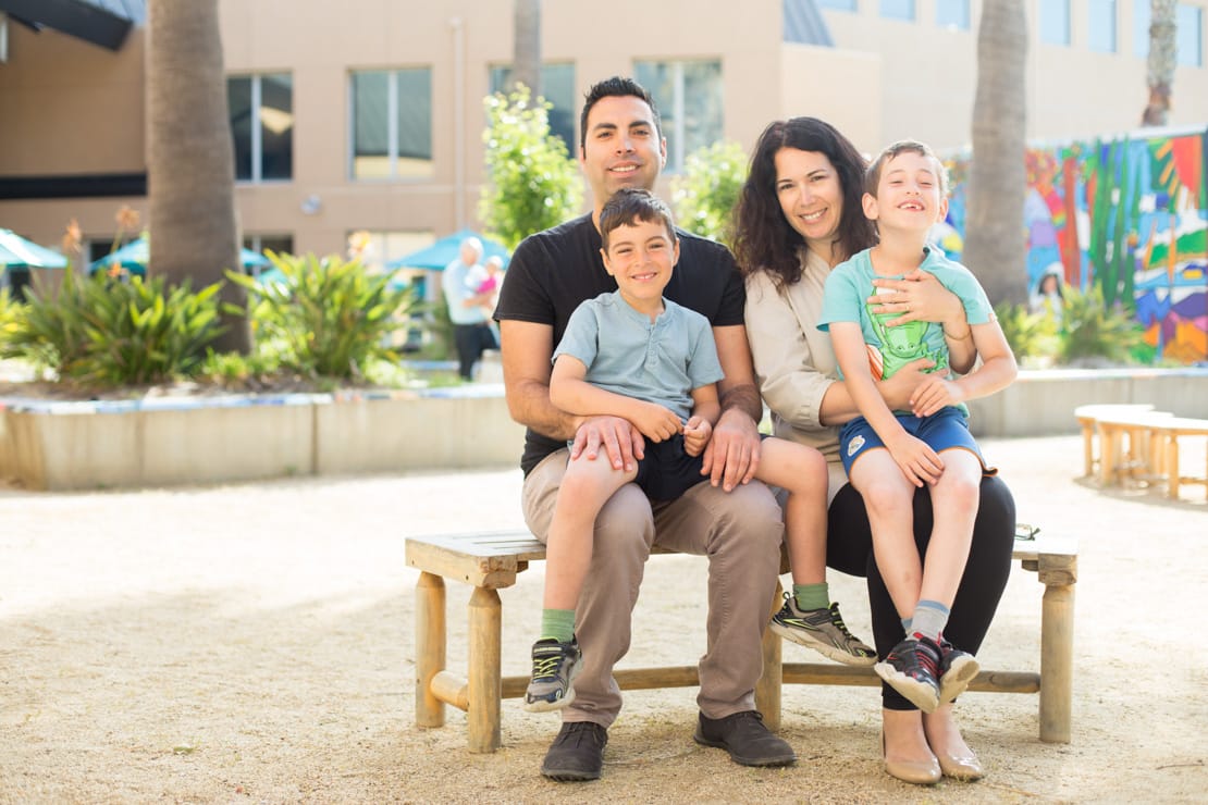 Parents and two kids on a bench smiling outside