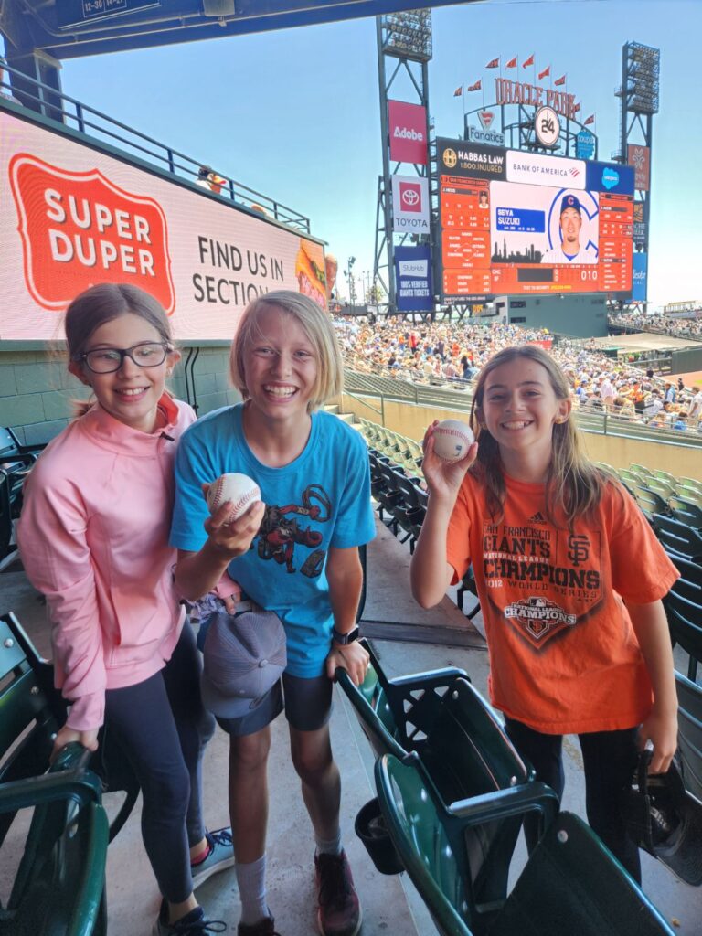 May contain three people at a baseball game, holding baseballs.