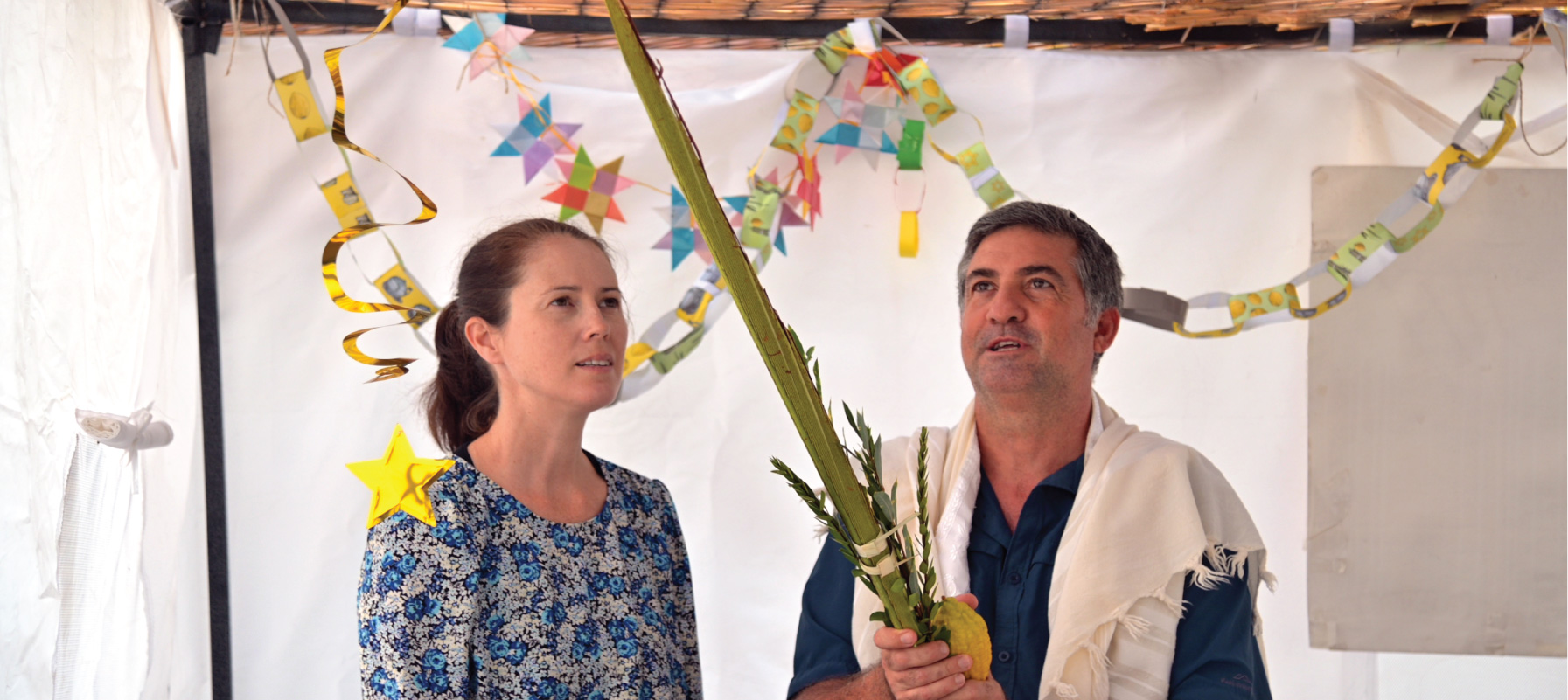 May contain two people celebrating a Jewish holiday, holding branches and fruit.