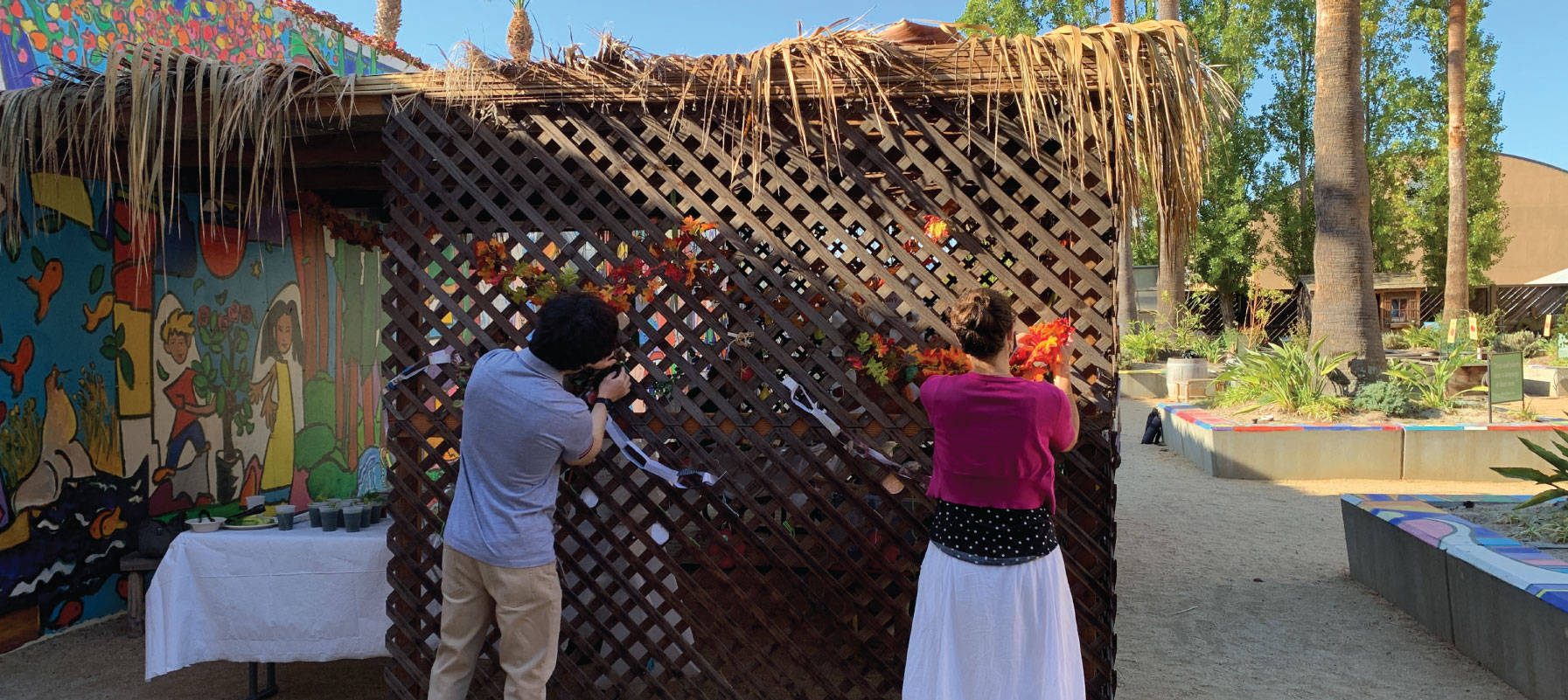 May contain two people working at a wooden sukkah.