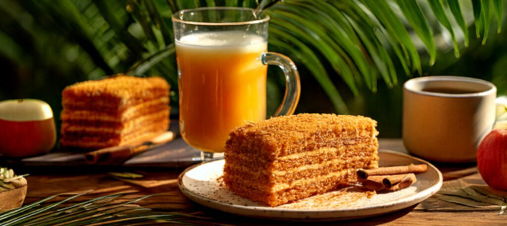 May contain a slice of layered cake, a glass of juice, a coffee cup, and apples.