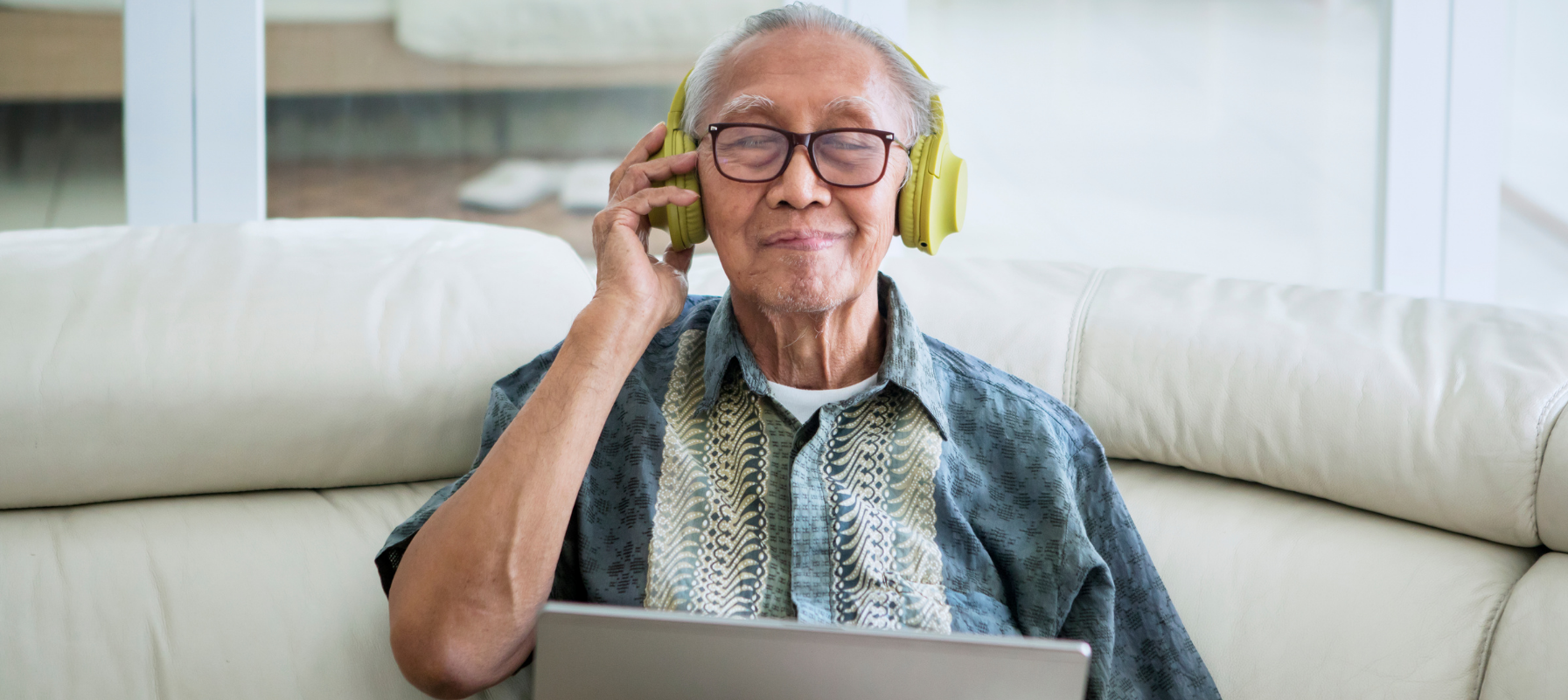 May contain a person wearing headphones and sitting on a couch with a laptop.