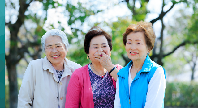 Group of three women standing together smiling and laughing